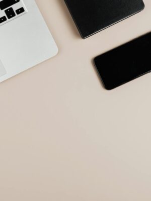 Modern workspace with laptop, smartphone, and eyeglasses on a beige surface. Ideal for tech or productivity themes.
