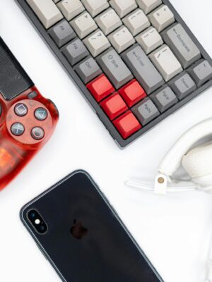 Top view of modern tech gadgets including gaming controller, smartphone, keyboard, and headphones.